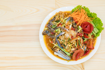 Papaya salad with BLUE SWIMMING CRAB on wood table.
top view of Tradition Spicy Thai salad - Thai cuisine (Som Tum poo)
