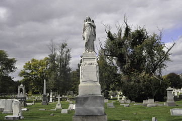 Fototapeta na wymiar Statue of an Angel in a Cemetery Landscape