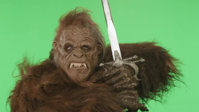 Bigfoot on a green screen with a sword, ready to battle