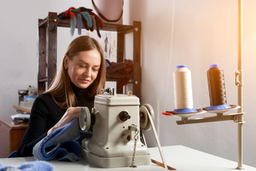 Young woman skinner sewing fur coat. Furrier at the factory in the neck fur coat in workshop