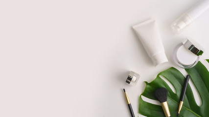 White cosmetic products and green leaves on white background. Natural beauty products for branding mock-up concept.