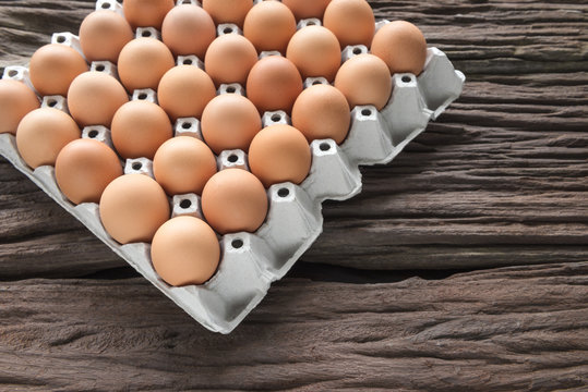Close-up view of raw chicken eggs in egg box on old brown wooden background