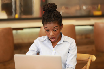 Amazed black girl using laptop