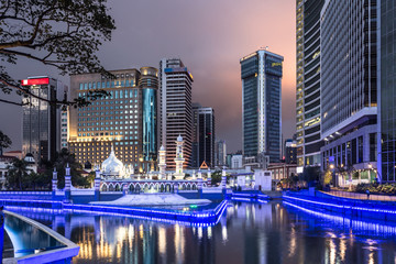 Naklejka premium The office buildings reflects in the water of the Klang river in front of the Jamek mosque in the heart of Kuala Lumpur in Malaysia.