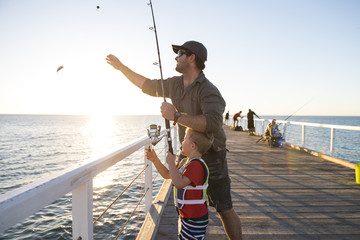 père enseignant au petit jeune fils à être pêcheur, pêchant ensemble sur le quai de la mer en profitant et en apprenant à l& 39 aide de la canne à poisson
