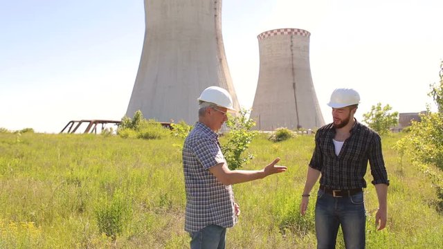 Two male architects shaking hands at construction site. Two men engineers shaking hands on a background of thermal power station.