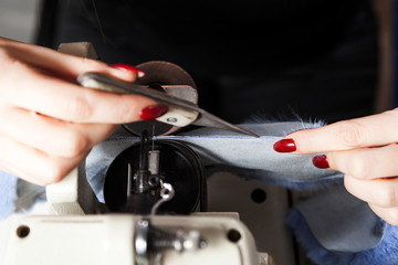 Close-up of a young woman furrier cutting a special knife with marked fur for making a female blue coat
