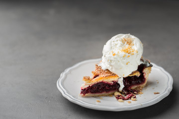 A piece of cherry pie with vanilla ice cream on a white vintage plate on a gray light concrete background. Copy Space. View blank space for text.
