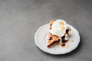 A piece of cherry pie with vanilla ice cream on a white vintage plate on a gray light concrete background. Copy Space. View blank space for text.