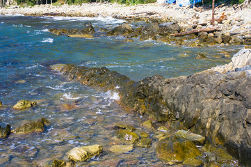 rocky sea shore with pebble beach, waves with foam