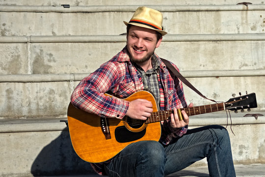 Young white smiling male playing acoustic slide guitar