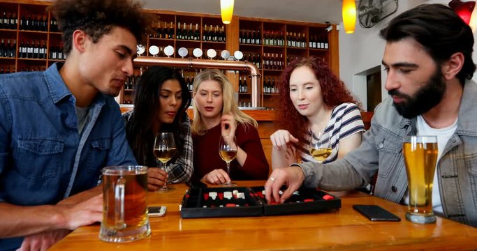 Friends playing backgammon while having drinks in bar 