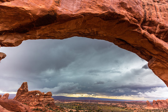 Storm clouds, rain, and red geologic sandstone structures in the Utah desert, Arches National Park © Calin Tatu