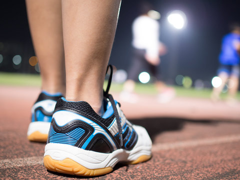 Runner Step On Track With Background Of Other Runner, Night Time.