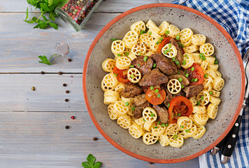 Fried chicken liver with tomato and garnish of pasta. Top view