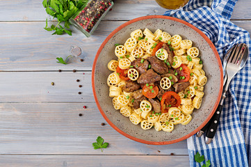 Fried chicken liver with tomato and garnish of pasta. Top view
