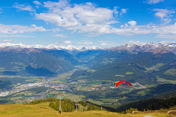 Paragliders take off near ski lift with Austrian Alps mountain range, view from Mount Kronplatz,...