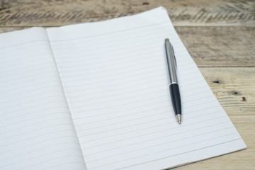 pen on white paper on wooden background.