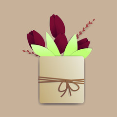 Bright red tulips in a square pot with a rope and a tiny bow. There are springs and leaves also.