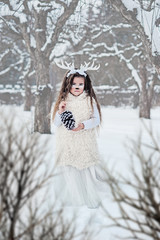 fairy tale girl. Portrait a little girl in a deer dress with a painted face in the winter forest