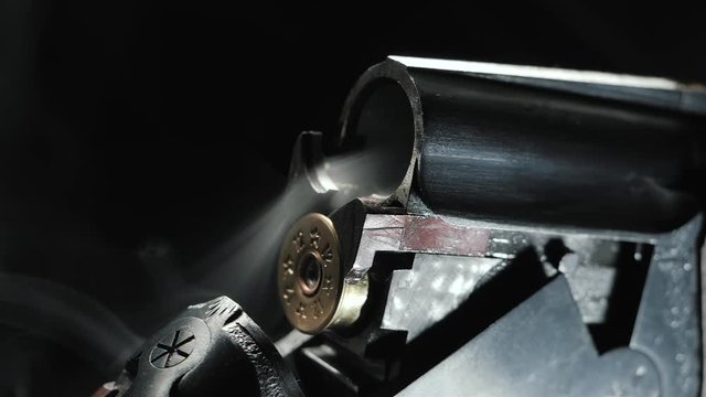 Smoke from the trunks of smooth-bore hunting rifle after firing. Slow motion. Black background.