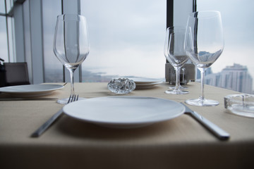 Empty white Plates on table at a restaurant with a large window view.