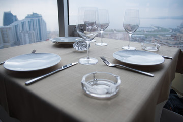 Empty white Plates on table at a restaurant with a large window view.