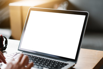 Mockup image of business man using and typing on laptop with blank white screen and coffee cup on glass table in modern loft cafe, Soft focus on vintage wooden table.