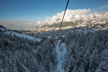 Red gondola car lift on the ski resort over forest trees