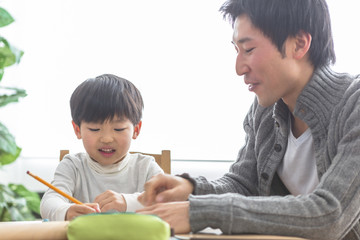 勉強する子供と勉強を見る親