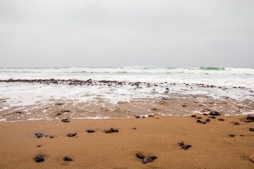 Coast, waves and beach with yellow sand and pebbles