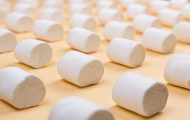 Sweet marshmallows on pastel yellow background.