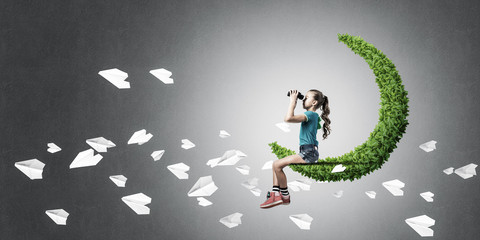 Concept of careless happy childhood with girl on green moon