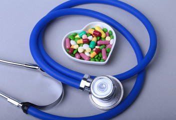 Stethoscope, RX prescription and colorful assortment pills and capsules on plate.