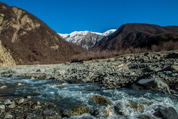 Stream river and mountain landscape. Snowy peak in distance