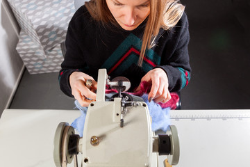 Close-up of a young furrier woman will process natural fur on a sewing machine to make a woman's fur coat, top view