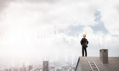 Engineer man standing on roof and looking away. Mixed media