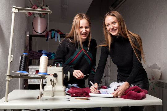 Close-up, two furrier women smile and discuss how to cut a fur coat from natural fur, on the table lie fur samples and a sketch of a fur coat - Powered by Adobe