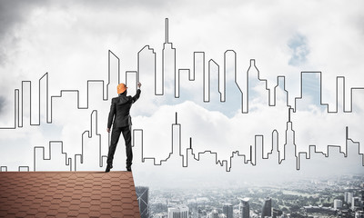 Man architect draw silhouette of modern city on blue sky. Mixed 