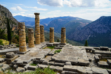 Fototapeta na wymiar Panoramic view of ancient ruin world heritage site at temple of Apollo with green olive groves valley, Parnassus mountain and blue sky background