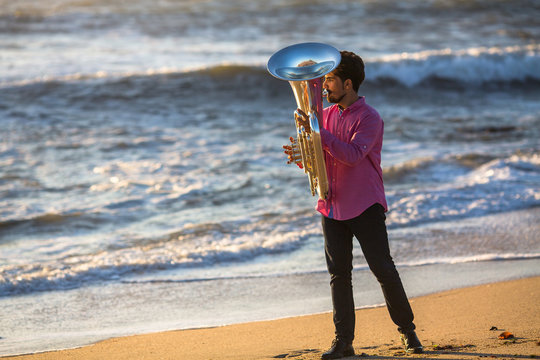 Man play the trumpet on Ocean coast during surf.