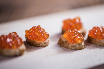 detail close up of red caviar salmon roe fish egg with baquette on white background