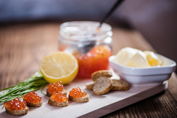 side view od tasty fresh salmon roe red caviar with butter and baquette on wood table 