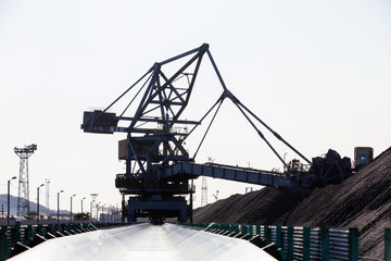 NAKHODKA, 2017: The place where the coal is being loaded into bulk cargo ship by big cargo cranes. Nakhodka bay, town of Nakhodka, the Far East of Russia. Aerial.