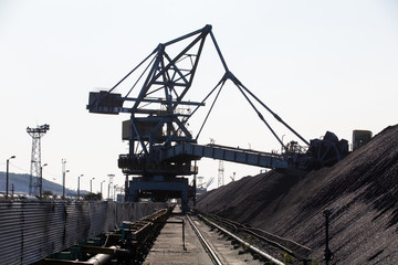 NAKHODKA, 2017: The place where the coal is being loaded into bulk cargo ship by big cargo cranes. Nakhodka bay, town of Nakhodka, the Far East of Russia. Aerial.