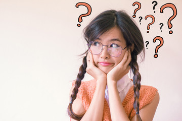 Young asian Student woman thinking with question marks doodles at the back ground with copy space