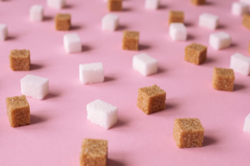 White and brown cane sugar cubes scattered on a pink background. Texture background