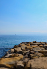 Fototapeta na wymiar Dock made of rocks and the open sea, shallow depth of field. San Remo, Italy.