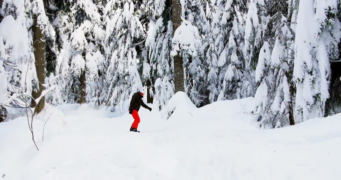 Man snowboarding through forest 