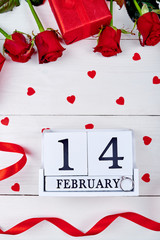 Valentines Day background with red roses, gift box, ribbon, hearts and diamond ring on wooden block calendar february 14 , copy space. Greeting card mockup. Love concept. Top view, flat lay